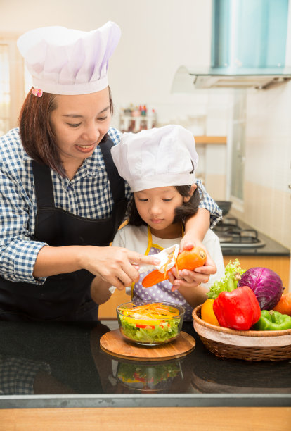 一位亚洲母亲在厨房教女儿做沙拉图片下载