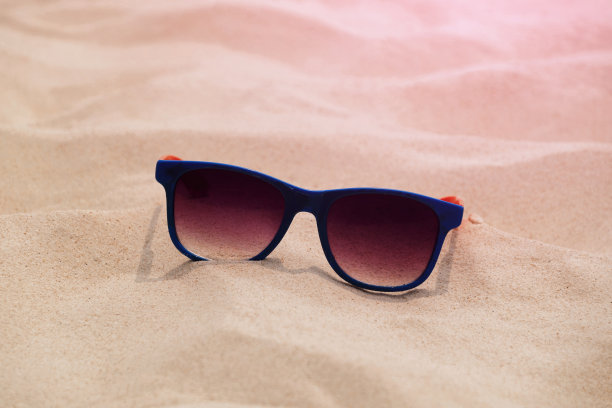 夏日沙滩上的太阳镜，海边旅行的时尚配件，保护眼睛免受阳光照射图片下载