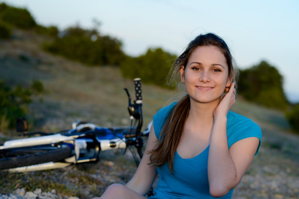 健康愉快的年轻女子骑自行车在户外日落图片下载