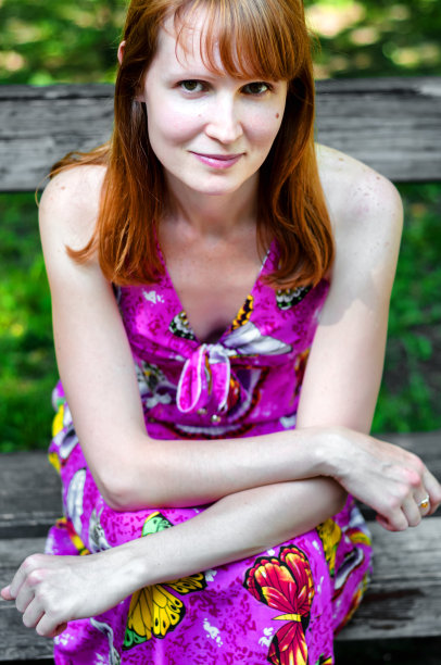 红头发的成年女孩穿着粉红色的衣服坐在长凳上图片下载