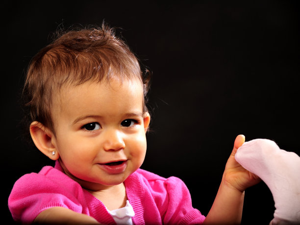 小女孩拿着脚，看着镜头微笑。图片下载