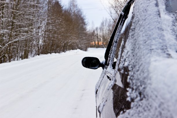 冰冻的黑色汽车在冬天的森林道路上图片下载