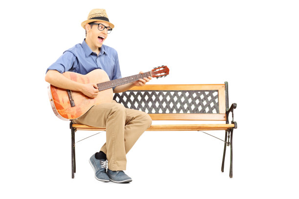 欣喜若狂的年轻吉他手坐在长凳上唱歌图片下载