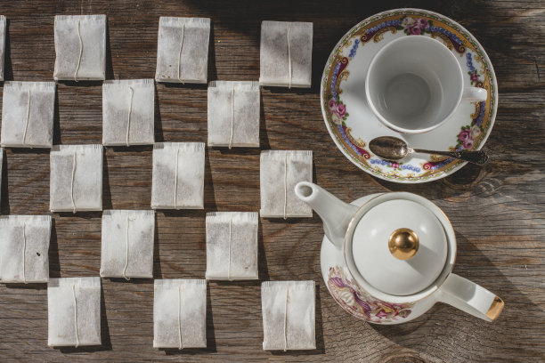 茶包摆放在木质背景上，配有茶杯和茶托图片下载