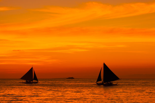 热带海上日落时的帆船。剪影照片。图片下载