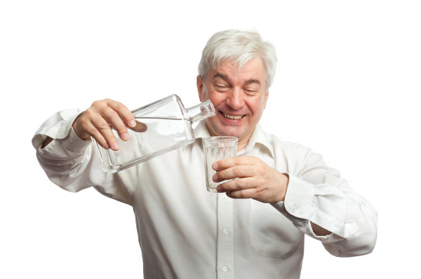 在白色背景下往玻璃杯里倒伏特加。图片下载