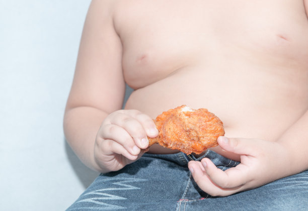 炸鸡在胖男孩的手里。图片下载