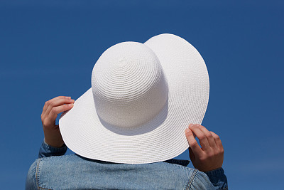 拿着白色太阳帽的女人图片下载