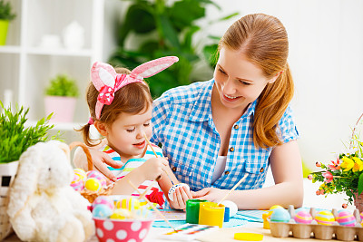 快乐的家庭母亲和孩子女孩画复活节彩蛋图片下载