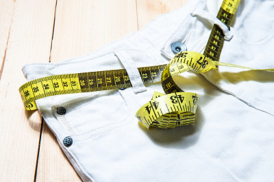 木制背景上的牛仔裤与卷尺的俯视图图片下载