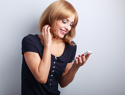 幸福微笑的金发女人在看手机短信图片下载