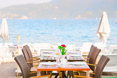 在海边的沙滩上的一个餐桌咖啡馆图片下载