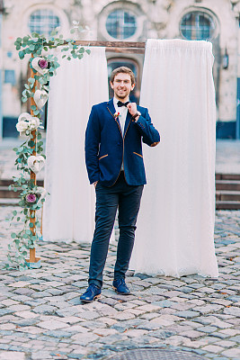 以婚礼拱门为背景的时尚新郎图片下载