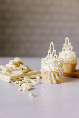 老式桌子上放着白巧克力和椰子做的纸杯蛋糕。图片下载
