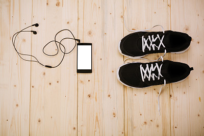 地板上的跑鞋和戴着耳机的电话图片下载