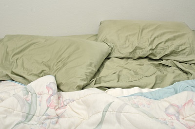 不整洁的床，枕头和毯子图片下载