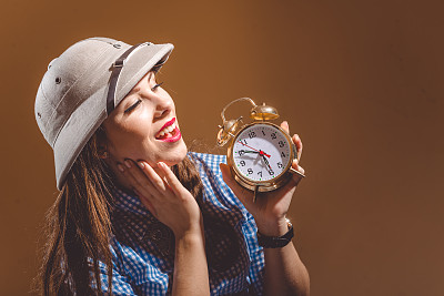 年轻女子戴着木髓头盔抱着闹钟睡觉图片下载