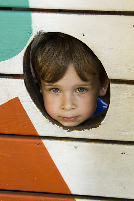 小男孩往木栅栏后面看图片下载