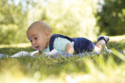 三个月大的婴儿躺在公园的草地上。图片下载
