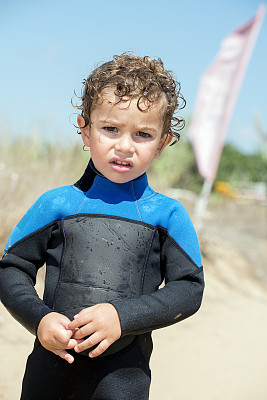 一个穿着潜水服的小男孩在海滩上的肖像图片下载