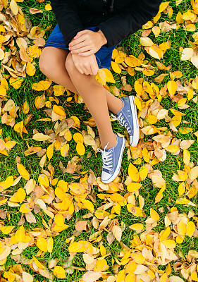 姑娘们坐在绿草如茵的草叶上，抱着秋天的概念图片下载