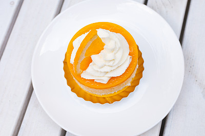 白色盘子上的橙色蛋糕和配奶油的木桌图片下载