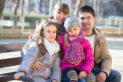 带着小女儿坐在长椅上的父母图片下载