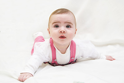 可爱的小女孩躺在白色的床上图片下载