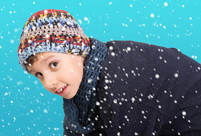 冬天可爱的小男孩在飘落的雪下图片下载