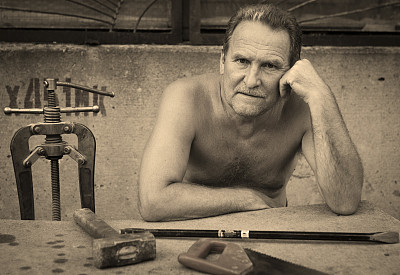 一位老人拿着锁匠工具坐在桌旁图片下载