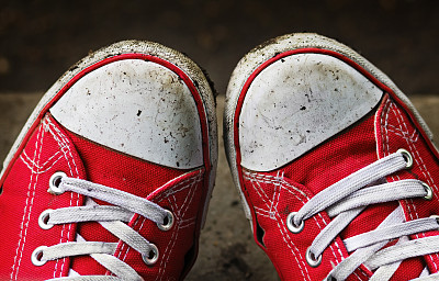 穿着肮脏的红色运动鞋和牛仔裤的脚在户外。图片下载