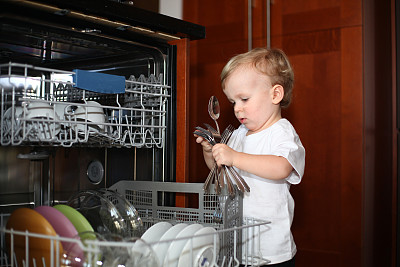 小男孩从洗碗机里取出银器图片下载