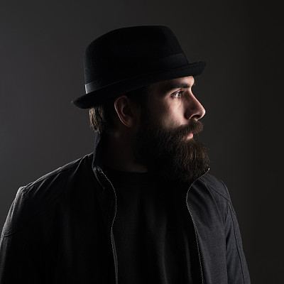 戴着帽子看向别处的大胡子男子的侧面视图。图片下载