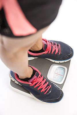 特写年轻的健身男子的脚在体重秤上图片下载