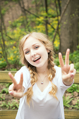 迷人的金发女孩露出模糊的和平标志和微笑图片下载