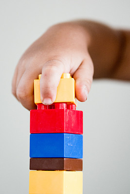 白色背景下手持玩具块的特写镜头图片下载