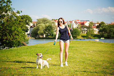 年轻女子和她的狗在公园散步图片下载