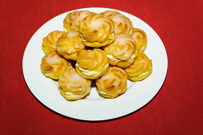 奶油泡芙堆在白色盘子上图片下载