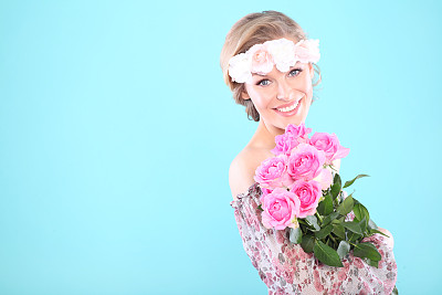 美丽的年轻女子拿着粉红色的玫瑰。图片下载