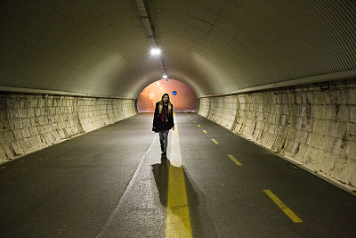 年轻的女士在黑暗中独自走过一条隧道图片下载