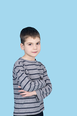 一个小男孩在蓝色背景下看着摄像机图片下载