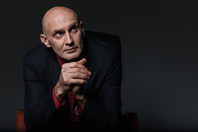 沉思的商人坐在办公椅上思考图片下载