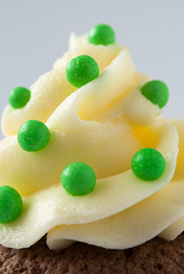 奶油蛋糕上的绿色糖果和巧克力纸杯蛋糕的特写图片下载
