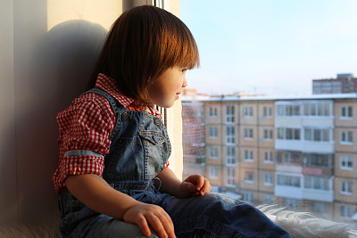 可爱的小男孩在冬天望着窗外图片下载