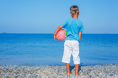 在海滩上玩球的男孩图片下载