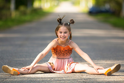 快乐的小女孩坐在马路上。图片下载