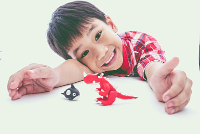 孩子在白色的背景上展示他的陶土作品。图片下载