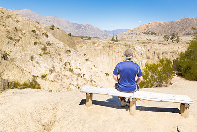坐在玻利维亚拉巴斯月亮谷长凳上的人。图片下载