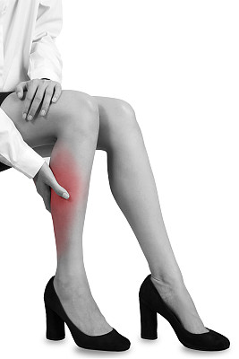 妇女抱着她的小腿疼痛部位，呈黑色和白色。图片下载