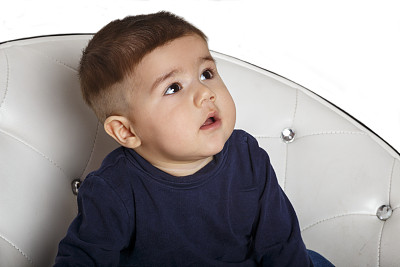 一个坐在椅子上的孩子的肖像。在白色背景上隔离图片下载